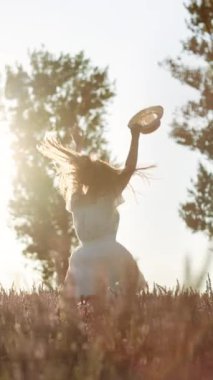 Parktaki lavanta tarlasında Özgür Kız eğlencesinin dikey videosu. Tarım kızı rüyası. Kadın çiftçi el ele verip tarlayı geçiyor. Lavanta tarlasında elinde şapkası olan bir kız..