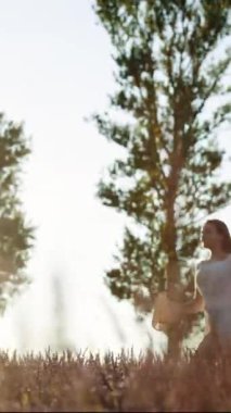 Günbatımında güzel mor lavanta tarlasında koşan beyaz elbiseli bir kadının dikey format videosu. Altın saat. Fransız Kaynağının Lavanta Tarlalarında Lavanta Mor Aromatik Çiçekler
