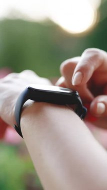 Kadın bileğinde Smart saatinin dikey format videosu. Fitness bilekliğinin nabzını kontrol et. Akıllı seğirme. Akıllı saat kullanan genç bir kadın. İzleme uygulaması girerken kadın dokunmatik ekranda.