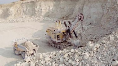 Büyük bir elektrikli kova kazıcısı büyük bir çöp kamyonuna kömür yüklüyor. Madencilik endüstrisi. Ağır sanayi