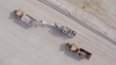 Bir kazıcının, ezilmiş bir taş ocağındaki bir çöp kamyonuna ezilmiş taş yüklediği hava üstü görüntüsü. Madencilik endüstrisi. Ağır endüstri. Demir cevheri ocağındaki akıllıca bir işlem.