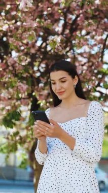 Mutlu bir kadının cep telefonundaki başarısını gösteren dikey format videosu. Kapalı çekim neşeli kız telefonda iyi haberleri ağır çekimde okuyor. Şaşkın kadın telefonda zaferi kutluyor..
