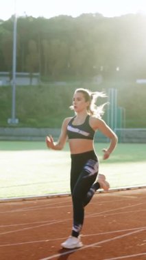 Beyazlı bir kadının spor giyim mağazasında spor pistinde spor yaparken çekilmiş dikey format videosu. Yetişkin bayan atlet koşu, maratondan önce antrenman. Sağlığa. Sporcu Kadın