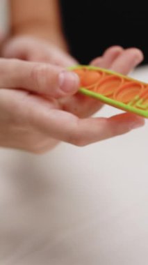 Kızın basit gamzeli gevşetici oyuncaklarla oynadığı dikey format videosu. Popüler masa oyunu oynayan çocuk, stres önleyici oyuncağı patlat. Çok renkli popüler silikon anti-stres oyuncağı patlat..