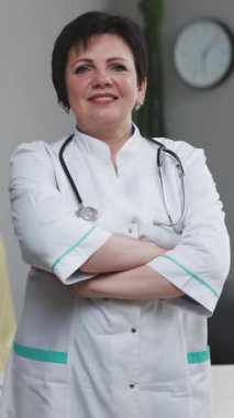 Yaşlı Doktor, düşünceli yaşlı kadın profesyonel sıhhiyecinin dikey videosu steteskop tutan beyaz önlük giyer ve hastane kamerasına bakar. Sağlık ve Sağlık Hizmetleri.