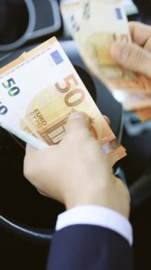 Avrupa ekonomisi için Avro para değerlerini sayarken Yakından Adam 'ın ellerinin dikey formatlı videosu. Avro banknotlarını sayan bir işadamı. Avro döviz kuru. Nakit para hesaplaması.