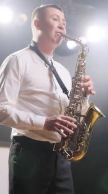 Şarkı söyleyen müzik grubunun düşey format videosu, ışıklarla konser veren bir müzisyen sahnesinde. DJ adam, saksafoncu saksafoncu, şarkıcı kız dansçı, gece kulübünde şarkı söyleyen.