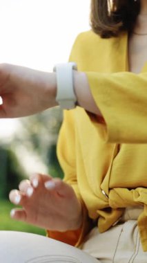 Şehirde akıllı dijital cihaz kullanan bir kadının dikey videosu. Akıllı saat. Akıllı sekte kaydırma ekranı. Akıllı saat uyarısı kontrol ediliyor. Dokunulabilir Ekran Giyilebilir Akıllı Bant.