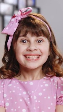 Pembe elbiseli şirin bir kızın elinde iki çörek tutarken çekilmiş dikey videosu. Sevimli ergen liseli kız tatlı çöreklerle oynuyor. Arka planda neşeli yüz ifadeleri yapıyor..