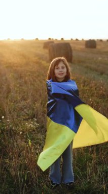 Mavi ve sarı Ukrayna bayraklı genç kızın dikey format videosu. Ukrayna 'daki savaşı durdurun. Rusya savaşı durdurur. Çocuk gün batımında dışarıda duruyor. Uluslararası demokrasi günü konsepti. Bayrak Günü.