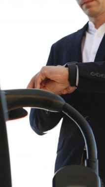 Erkek elinin dikey videosu, güç bağlantısını EV 'ye bağlar ve pilleri şarj eder, şarjı kesmek için akıllı saati kullanır. Adam akıllı yama kullanarak şarj kablosunu elektrikli araca bağlıyor..