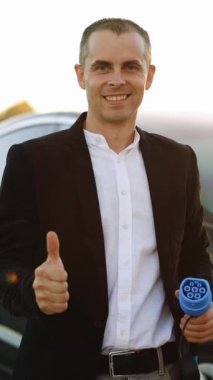 İşadamı 'nın dikey videosu, elektrik yüklü araba istasyonunda 2 cc' lik elektrik kablosu olduğunu gösteriyor. Elektrik şarj istasyonunun yanında duran ve parmağını gösteren bir adam..