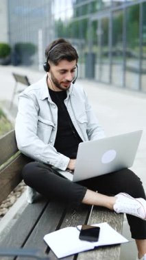 Erkeğin dikey format videosu kulaklık konferansı takıyor ve internetteki öğretmenle sohbet ediyor. Bilgisayar kameralı sohbet kullanarak öğrenen erkek öğrenci notlar alır. Uzaklık eğitimi kavramı