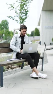 Kulaklık takan iş adamının video ile iletişim kurduğu dikey bir video. Laptop bilgisayarına bakan etnik işadamı konuşması, online konferans ofis sohbeti, sanal eğitim kavramı.