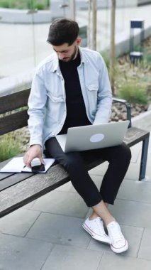 Akıllı telefon cihazıyla cep telefonu tutan sakallı adamın dikey format videosu. Gülümseyen genç Ermeni blog yazarı yeni sosyal medya aboneliği yapıyor, internetten alışveriş yapıyor, uygulamalardan ürünler sipariş ediyor.