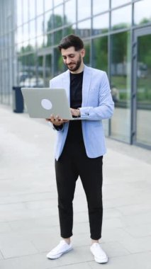 Bilgisayarda çalışan, borsa verilerini kontrol eden, bilgisayara bakıp gülümseyen genç beyaz sakallı yakışıklı adam videosu. Gülümseyen başarılı bir broker. İşadamı.