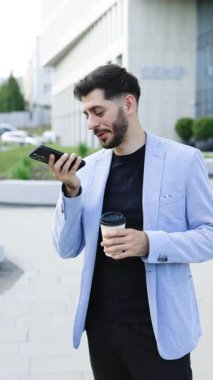 Arkadaşlarıyla hoparlörde konuşan sakallı bin yıllık iş adamının dikey videosu ses tanıma programını mobil uygulama üzerinde sanal yardımcı dijital uygulama kayıt ses mesajı ile çalıştırıyor.