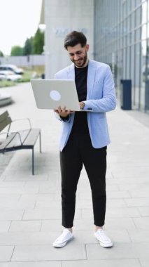 Bilgisayarda çalışan, borsa verilerini kontrol eden, bilgisayara bakıp gülümseyen genç beyaz sakallı yakışıklı adam videosu. Gülümseyen başarılı bir broker. İşadamı.