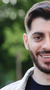 Dışarıda dikilen güzel kahverengi gözlü sakallı adamın yarım yüz videosu. Moda saç stili olan şehvetli adam kameraya bakıyor. Kameraya bakıp gülümseyen bir erkek portresi.