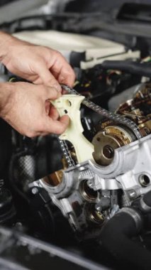 Aracı kullanarak otomobil tamir eden tamircinin dikey videosu. Araba tamircisi araba servisindeki motoru tamir ediyor. Otomobil ustası araçtan motoru tamir ediyor. Garajda ya da atölyede çalışan tamirci.