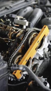 Parçalanmış motorun dikey videosu. Tamirci, aracı kullanarak motoru tamir ediyor. Araba tamircisi motoru tamir etti. Tamirci garajda ya da atölyede çalışıyor. Araba ya da motorsiklet kullanan bir adam..