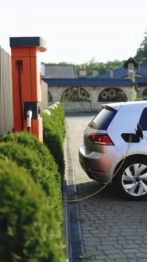 Yükleme istasyonundaki elektrikli araç parkının dikey format videosu. Elektrikli araç pili şarj oluyor. EV 'de sıfır emisyon aracı park halinde.