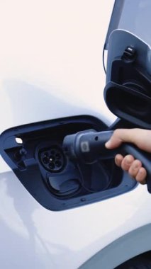 Elektrikli arabanın sürücüsünün dikey videosu pilleri şarj etmek için elektrik konnektörünü yerleştirir. Elektrikli arabaya elektrik kablosu bağlayan adam. Elektrikli araç şarj portu yeniden yükleniyor.