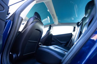 Modern elektrikli arabanın panoramik cam güneş çatısı. İçeriden ya da içeriden temiz bir açılır tavan ve gökyüzü manzarası. Arka koltuklu boş arabanın manzarası..