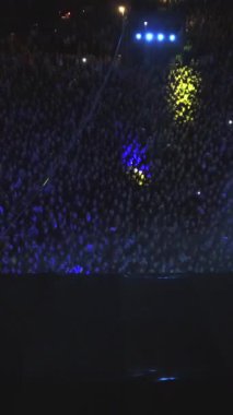 Gece bir açık hava müzik konserinin Top view 'in dikey format videosu. Dans pistindeki insanlar konseri ve en sevdikleri müzik grubunu alkışlıyorlar..