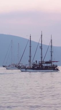 Porto Montenegro, Tivat, Montenegro Yachts in marina dikey format videosu. Güzel, sakin bir gün batımı ve denizde bir yat..