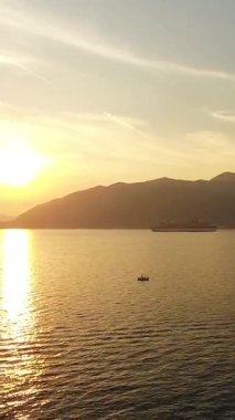 Porto Montenegro 'daki lüks marinada günbatımında yatların dikey videosu. Güneşe karşı uçuş. Karadağ 'ın Tivat kentindeki Porto Karadağ Kotor Körfezi' ndeki dağların üzerinde turuncu gün batımı. Avrupa