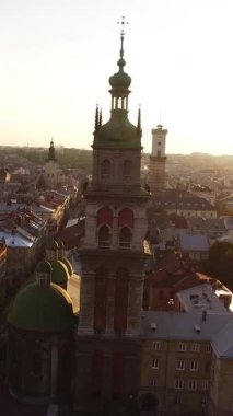 Şehir Merkezi, Belediye Binası ve Kilise 'nin Lviv Aerial Drone görüntüsü üzerinde Sunset' in dikey videosu. Günbatımında Ukrayna 'nın görkemli Lviv kentindeki Latin Katedrali, Assumption Kilisesi ve belediye binasının otantik kuleleri