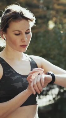 Smartwatch 'te Aktif Çalışanların Kalbini Kontrol Ettiği Dikey Biçim Videosu. Sağlıklı Kafkas Kadın Koşarken Fitness İzleyici Kullanıyor.
