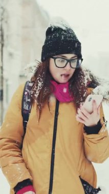 Neşeli hippi kızın dikey format videosu akıllı telefondaki e-posta kutusunu kontrol ederken alışveriş için indirim kazanmaktan heyecan duyuyor. Mutlu genç bayan haberi aldı ve piyangoyu kazandı..