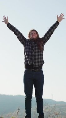 İnsanoğlunun ellerini çatıya atıp özgürlüğün tadını çıkardığı dikey bir video. Gelecekteki başarıya inan. Kendine güvenen erkek güneşin doğuşunu, başarısını ve ilhamı sever. Gökdelendeki turist zaferi