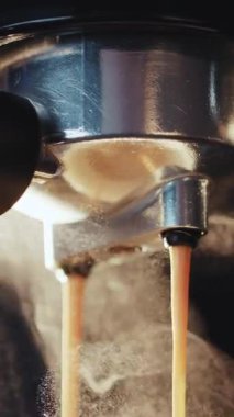 Kahve makinesinin fincana Espresso döktüğü dikey format videosu. Kahve makinesinden taze kahve çıkarıyorum. Sabahları sade kahve içmek.