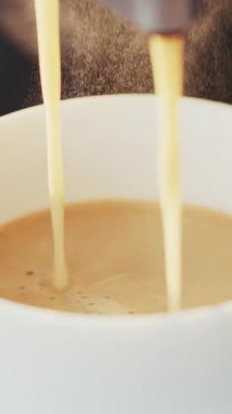 Kahve makinesinin fincana Espresso dökerkenki dikey videosu. Kahve makinesi kahve bardağında espresso yapıyor. Kafede buharla kaplanmış. Kahve makinesinden taze kahve çıkarıyorum.