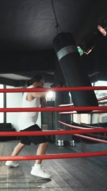 Erkek Boksörün dikey videosu ringe giriyor ve dövüş için hazırlanıyor. Ringde profesyonel boksör, vuruş tekniğini uygula, işkence, savunma ve dayanıklılık, eğitimde ıslak.