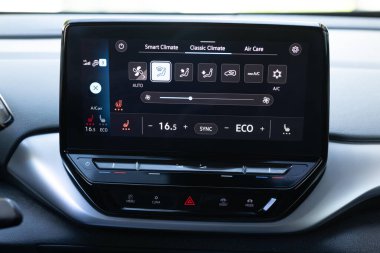 Isıtmalı koltukları tuşlara basarak çalıştırmak. Arabada ısıtmalı koltuk paneli. Direksiyon ısıtma düğmesi arabada. Direksiyon simidi ve koltuk ısıtıcısı olan elektrikli araba kontrol paneli.