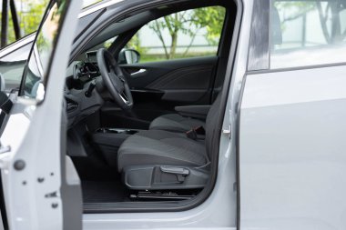 Elektrikli araba iç dekorasyonu ayarlamaları. Ön koltukları, sürücü ve yolcusu, tekstil, pencereler, konsol, vites kolu, elektrik düğmeleri, dijital hız göstergesi, direksiyon simidi olan arabanın içi.