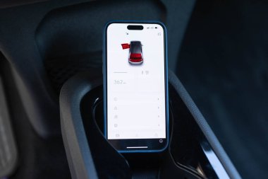 Elektrikli araba, servis, akıllı telefonlu açık kapı, güvenlik konsepti. Tanımlanamayan otomotiv teknisyeni, cep telefonunda arabanın kilidini açmak için özel bir uygulama kullanarak arabayı açıyor..