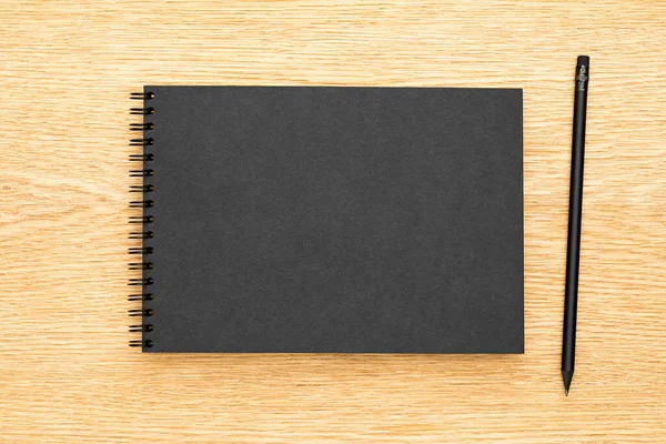黒い紙のノートブックのオークウッドデスクの背景 — ストック写真