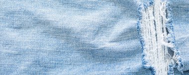 Açık mavi yırtık kot pantolon dokusu arka planı.
