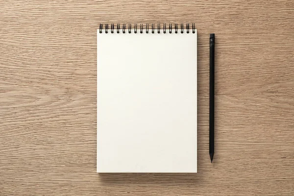 Stock image Notebook and black pencil on oak desk. Flat lay. Top view.