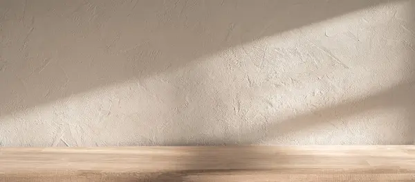 Yumuşak güneş ışığı, pürüzsüz ahşap bir yüzey ve dokulu bir duvar üzerine gölge düşürür. Öğleden sonra boyunca sakin ve davetkar bir atmosfer yaratır..