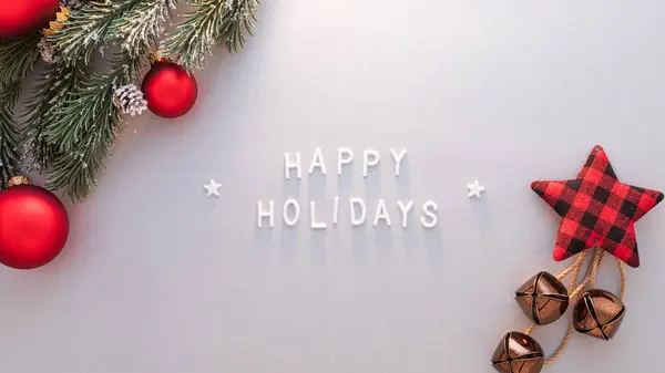 Parlak kırmızı süsler ve ekoseli bir yıldız neşeli bir Mutlu Bayramlar mesajına eşlik ederek mevsimsel kutlamalar için sıcak bir şenlik atmosferini çağrıştırıyor..