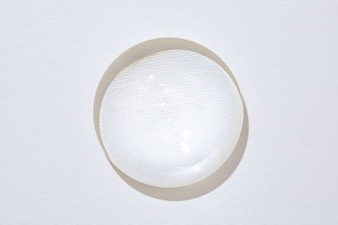 Kalıplı beyaz bir kağıdın üzerinde duran dairesel cam lensi temizle.