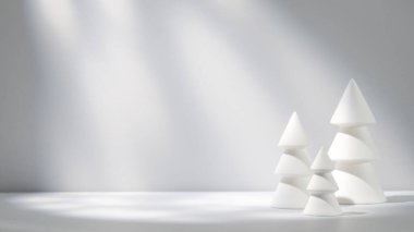 Minimalist beyaz Noel ağacı heykelleri hafif ışıkla aydınlatılmış yumuşak gri bir zemin üzerine kurulmuş..