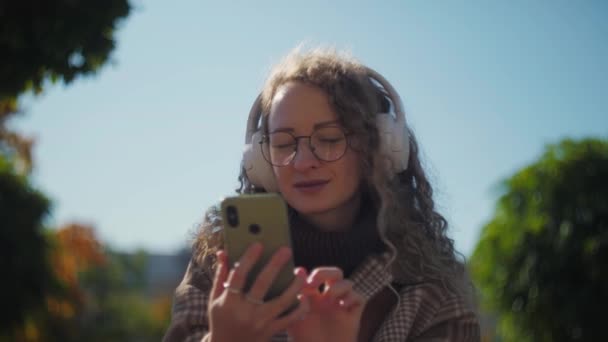 Γυναίκα Ακούει Μουσική Ακουστικά Στο Πάρκο Curly Κορίτσι Απολαμβάνοντας Χρήση — Αρχείο Βίντεο