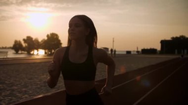 Gün batımının arkaplanına karşı parkta koşan genç kız. Sokakta koşan bir kadın. Düşük hareket. Yüksek kalite 4k görüntü
